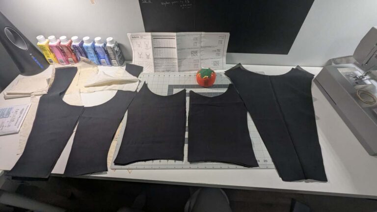 Black fabric pieces cut out from the corset pattern, ready for sewing.