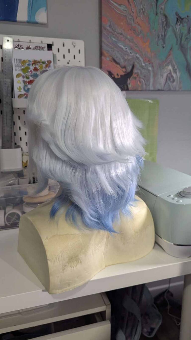 The white shoulder-length wig, dip-dyed blue on the bottom and styled into loose waves.