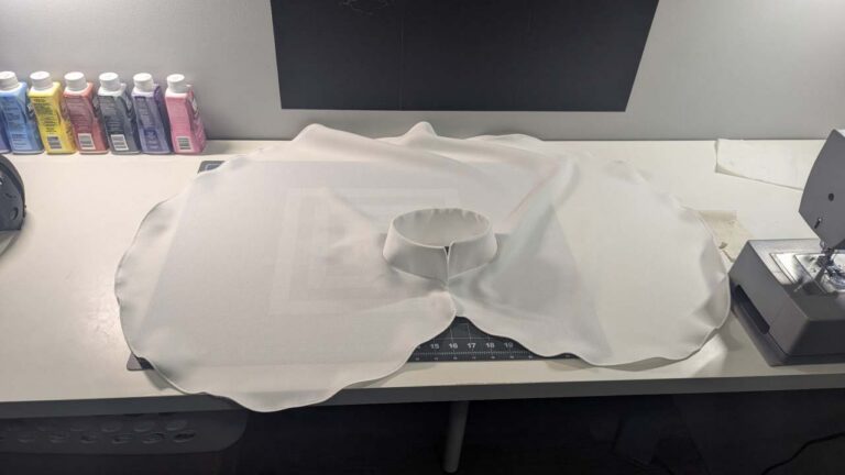 A capelet with a neck collar, cut from white flowing fabric.