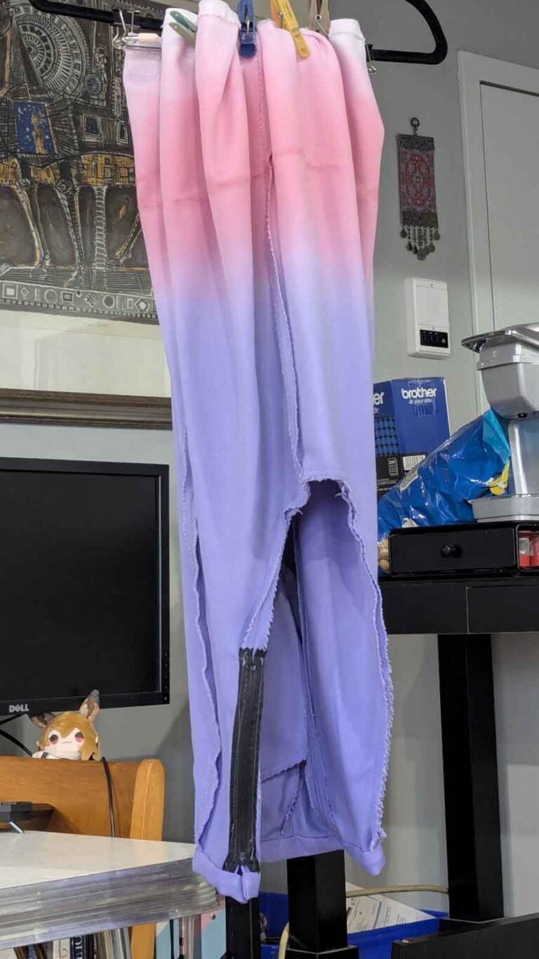 Pants have been dip-dyed in a gradient from pink to purple, and are hanging upside down to dry.