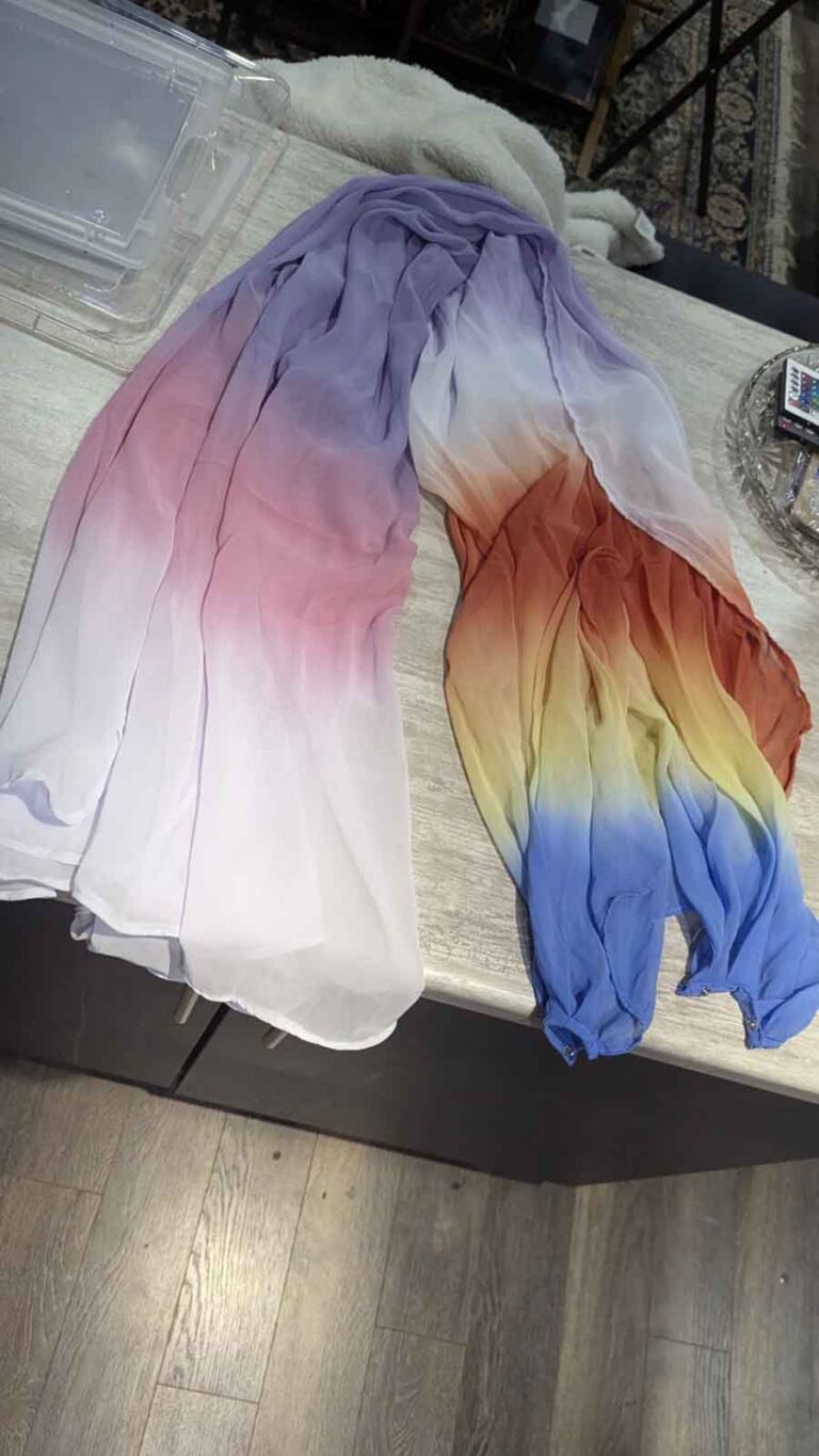 The long chiffon cape, drying after having been dyed pink, purple, red, yellow, and blue.