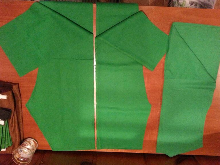 Green fabric cut out for the shirt and pants, ready for sewing.